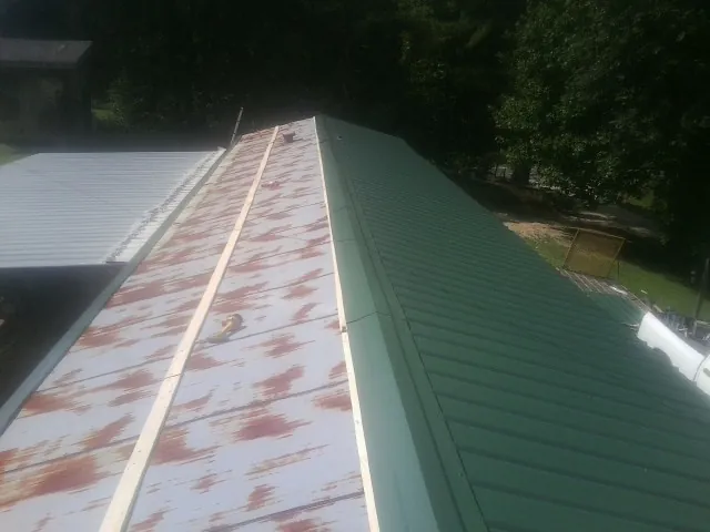 Old rusted panels beside newly installed green metal roofing — Wind Damage Roof Repair by Roofing Brothers in Goodlettsville