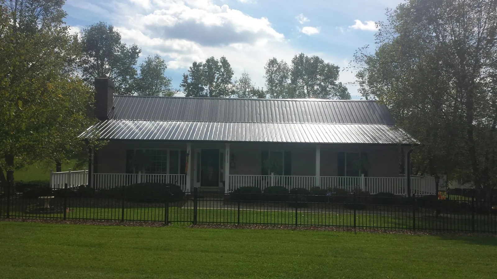 Gray metal roof on a brick ranch with a full width front porch — Gutter Guard Installation work by our crew in Goodlettsville
