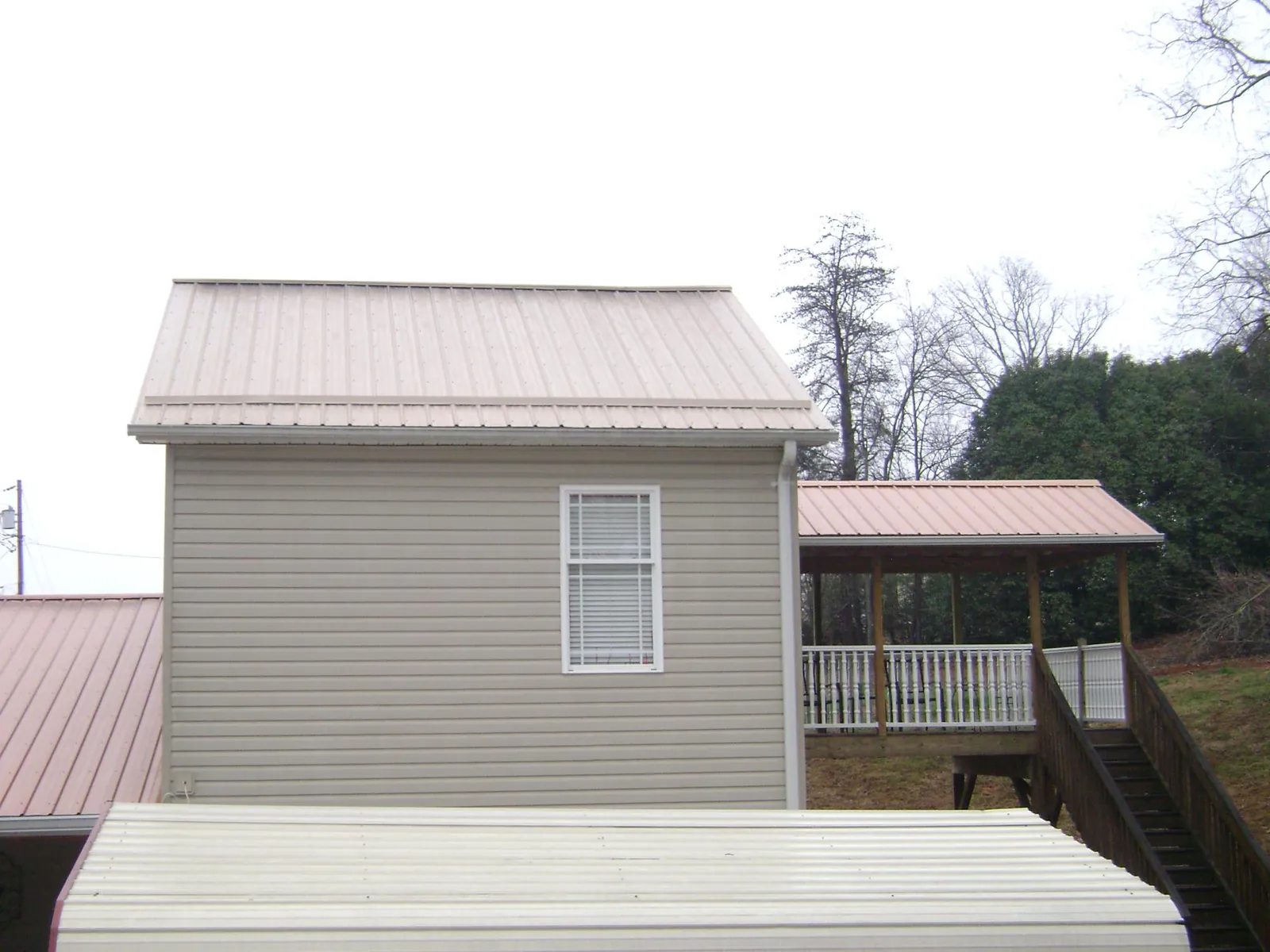 Tan metal roofs on a two story addition and attached porch, from a Roof Replacement job in Goodlettsville