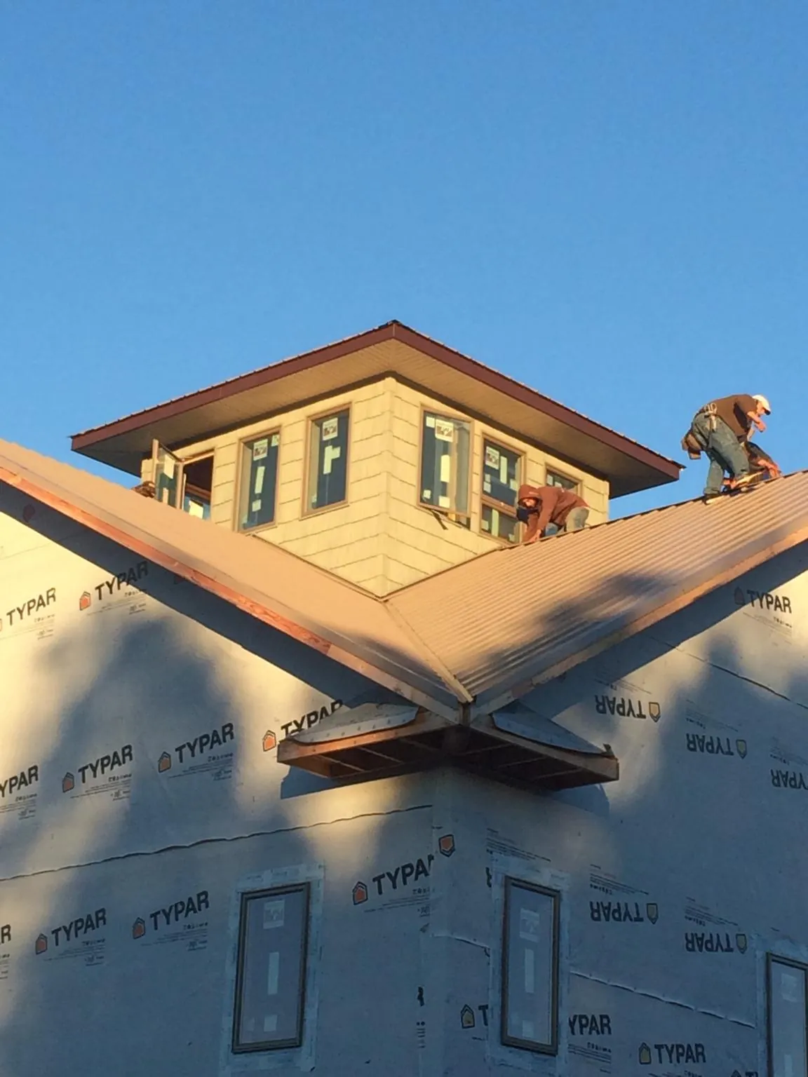 Roofers working around a rooftop cupola on a new metal roof at sunset — Roof Waterproofing in Goodlettsville by Roofing Brothers
